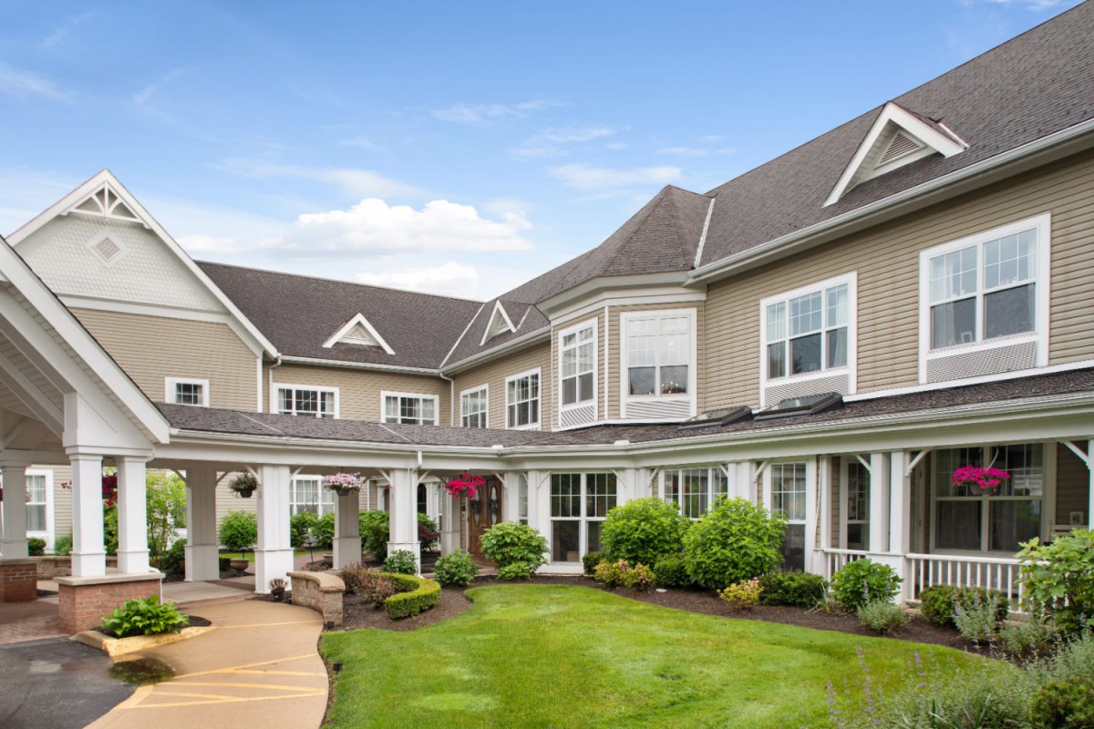 A view of a large suburban house with a landscaped garden and lawn.
