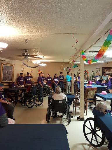 A community event featuring a group of people in purple shirts, gathered indoors, creating a lively atmosphere.