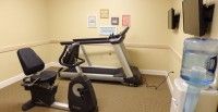 A treadmill in a small gym room with motivational posters on the wall.