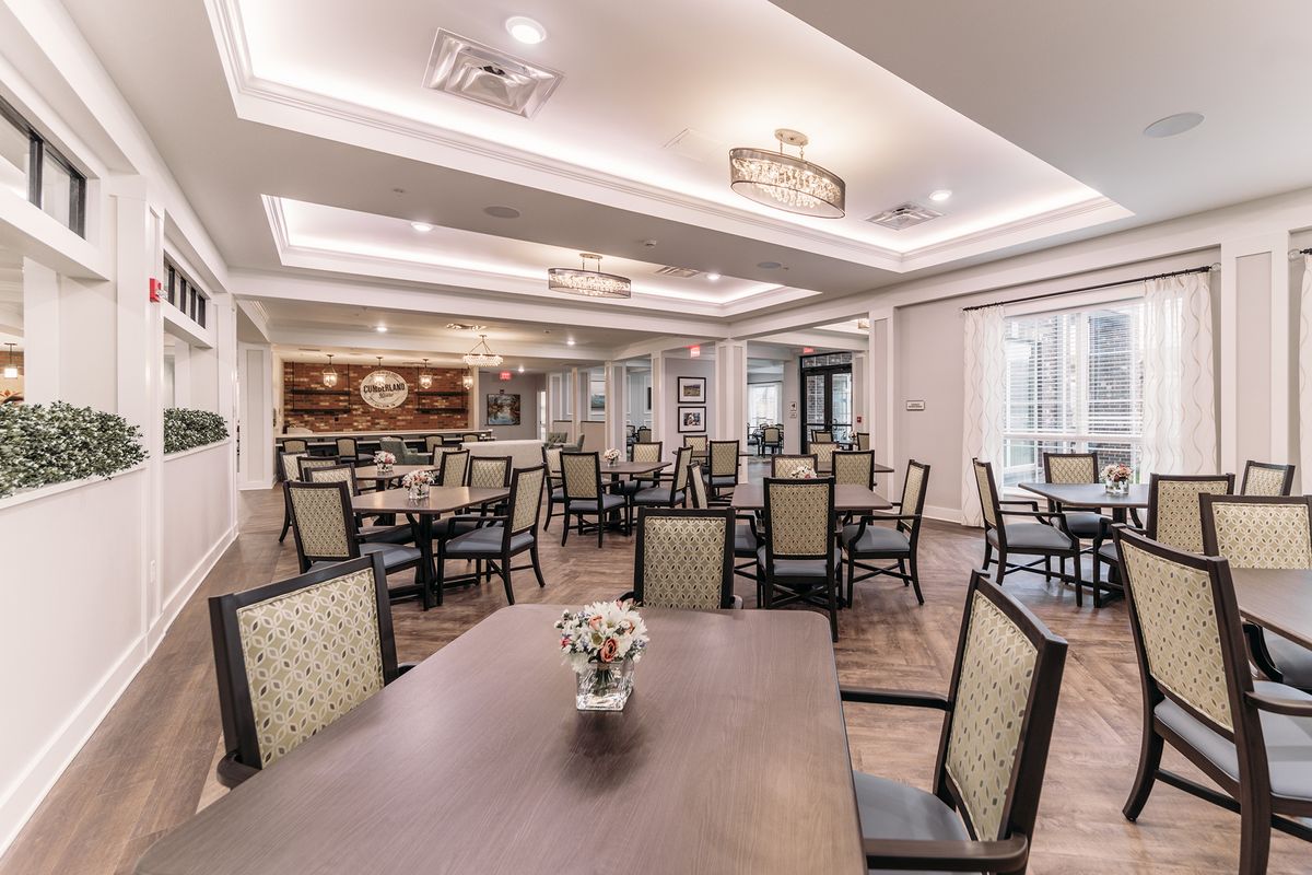 A spacious and elegantly decorated dining area with multiple tables and chairs, featuring stylish lighting fixtures.