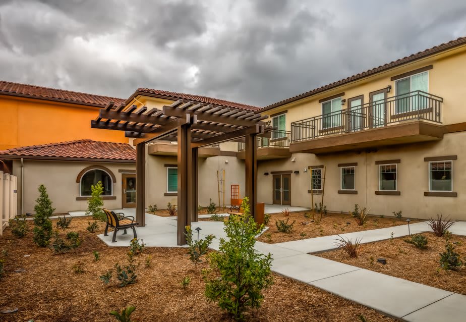 A view of a modern courtyard with a pergola and surrounding buildings under an overcast sky.