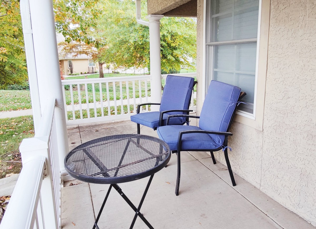 A cozy patio with two blue cushioned chairs and a small round table, ideal for relaxation.