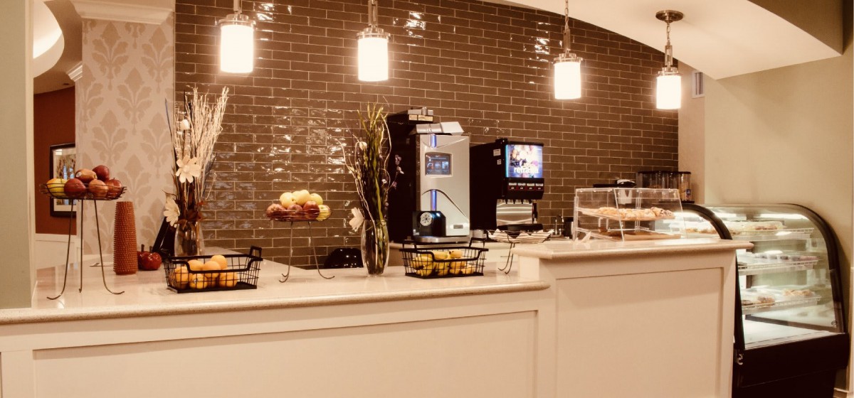 A cozy coffee shop counter with a beverage machine, snacks, and warm lighting.