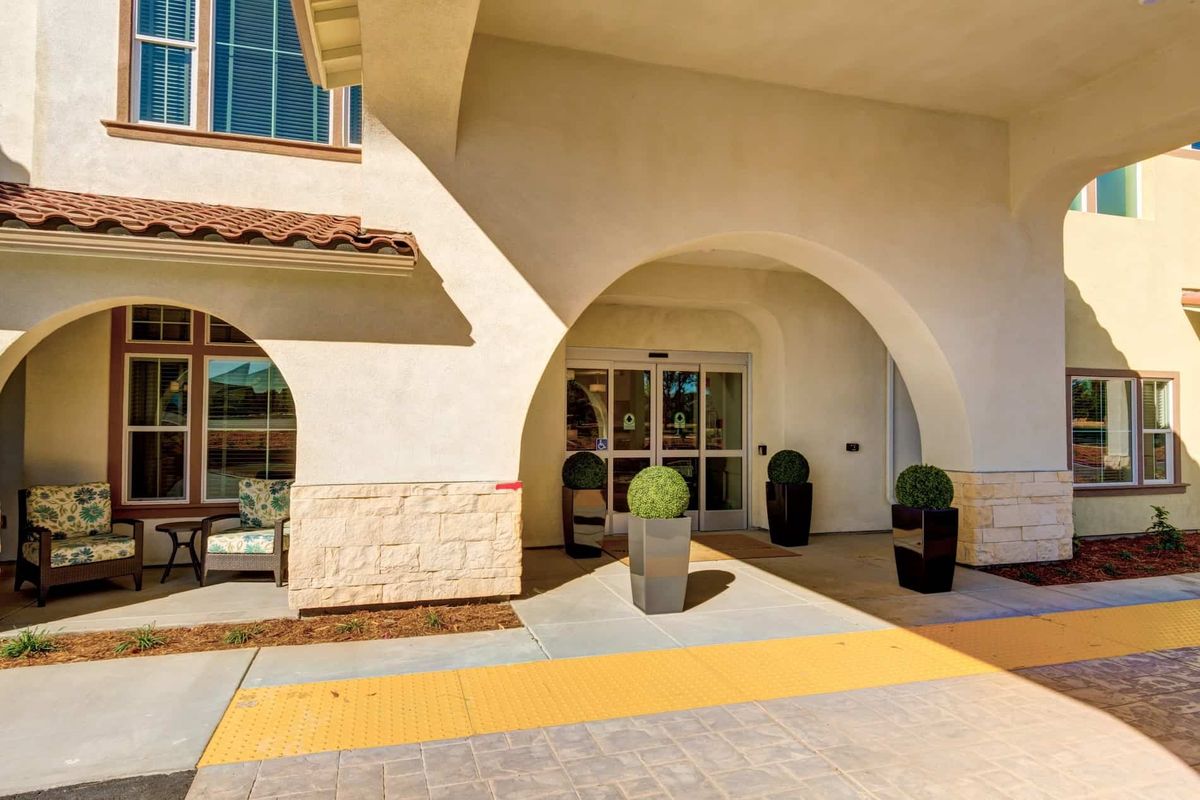 A modern building entrance with arched design and potted plants.