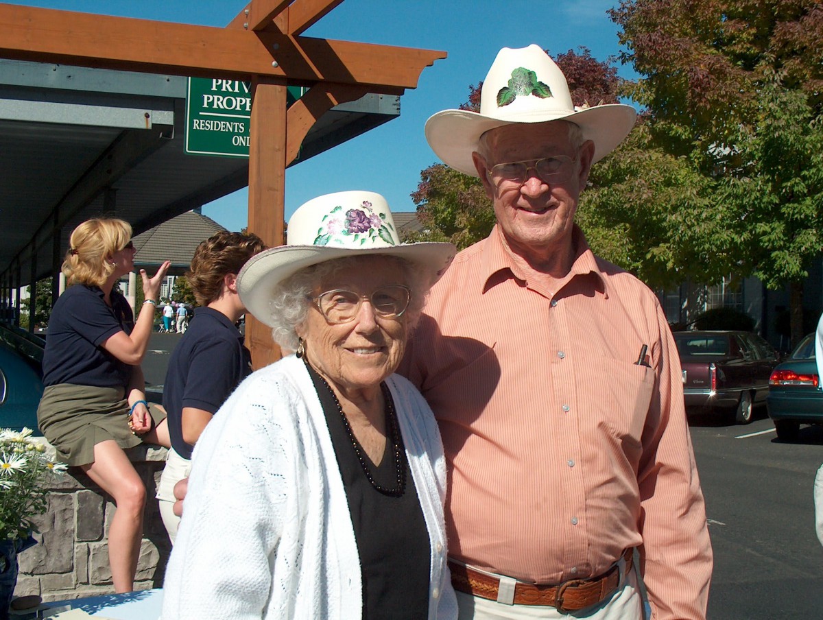An elderly couple wearing hats and casual clothing enjoying a sunny day outdoors.
