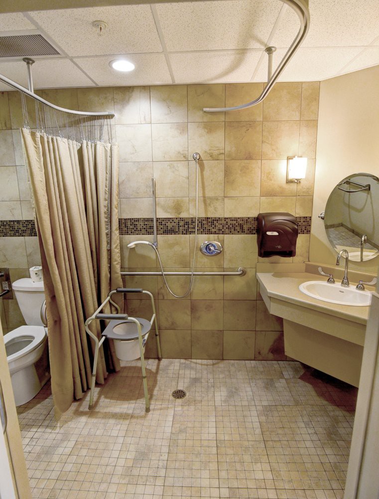 An accessible bathroom with a shower, sink, and toilet, featuring grab bars for support.