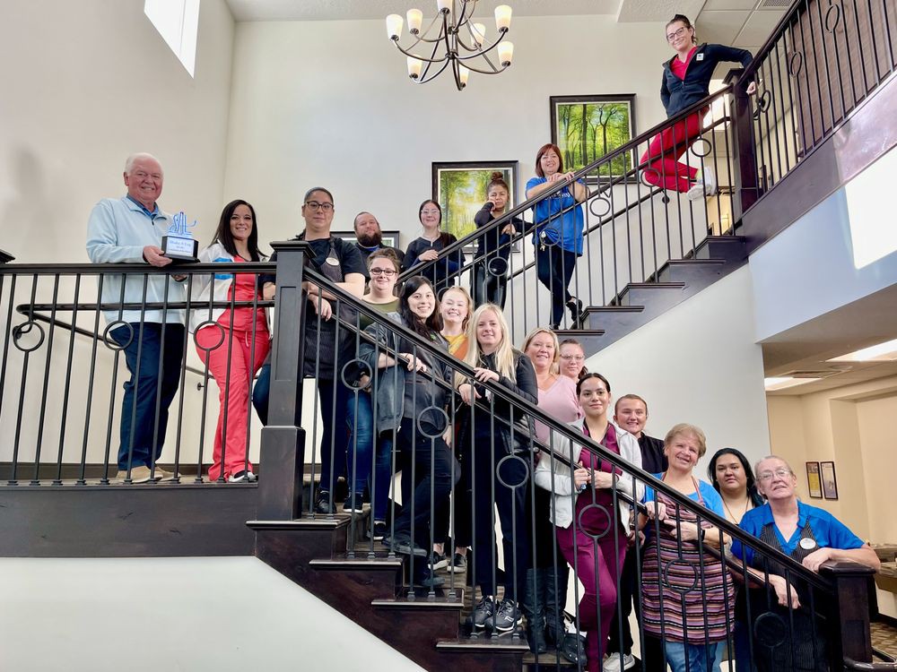 A group of people gather on a staircase for a group photo inside a building.