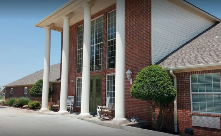 A brick building with large windows and white columns at the entrance.