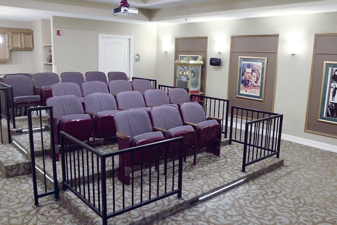 A cozy home theater setup with multiple rows of seating, a projector, and movie posters on the walls.