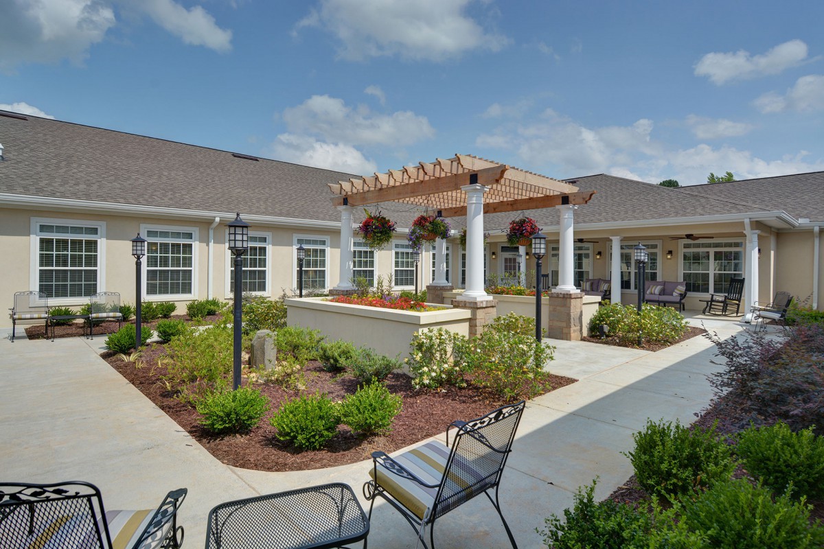 A beautifully landscaped courtyard with outdoor seating and a pergola on a sunny day.