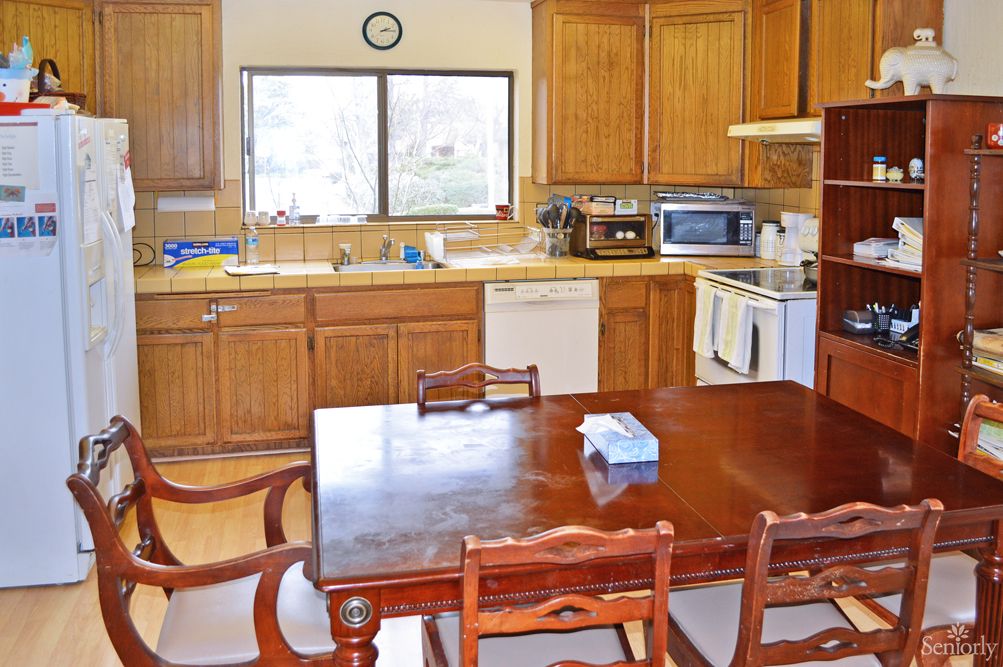 A spacious kitchen with wooden cabinets and a dining table set for meals.