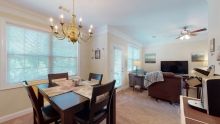 A cozy dining and living room area with a chandelier and wooden flooring.