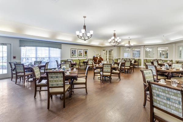 An elegantly furnished dining area with multiple tables and chandeliers.