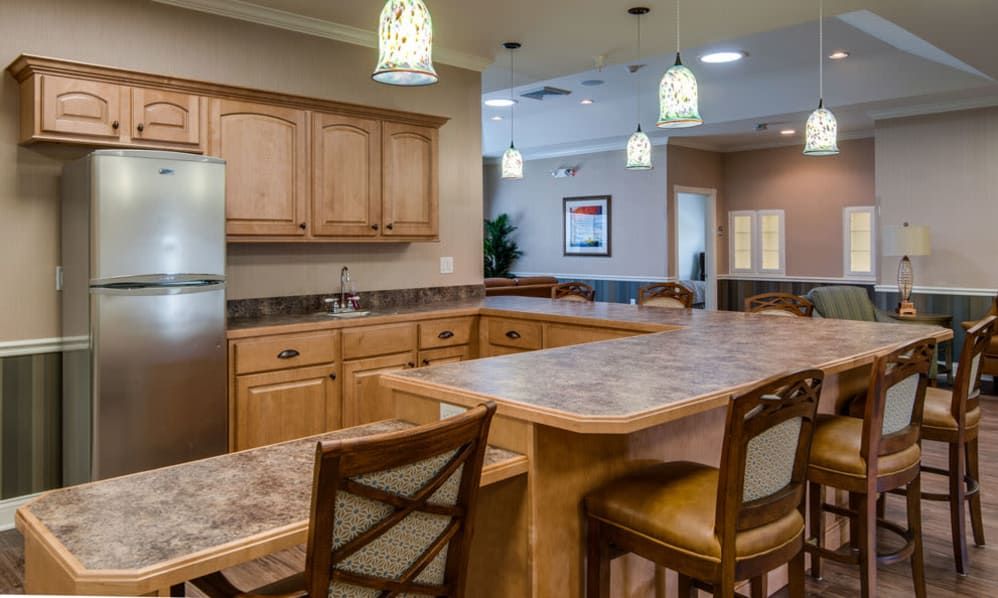 A modern kitchen interior featuring wooden cabinets and marble countertops with pendant lighting.