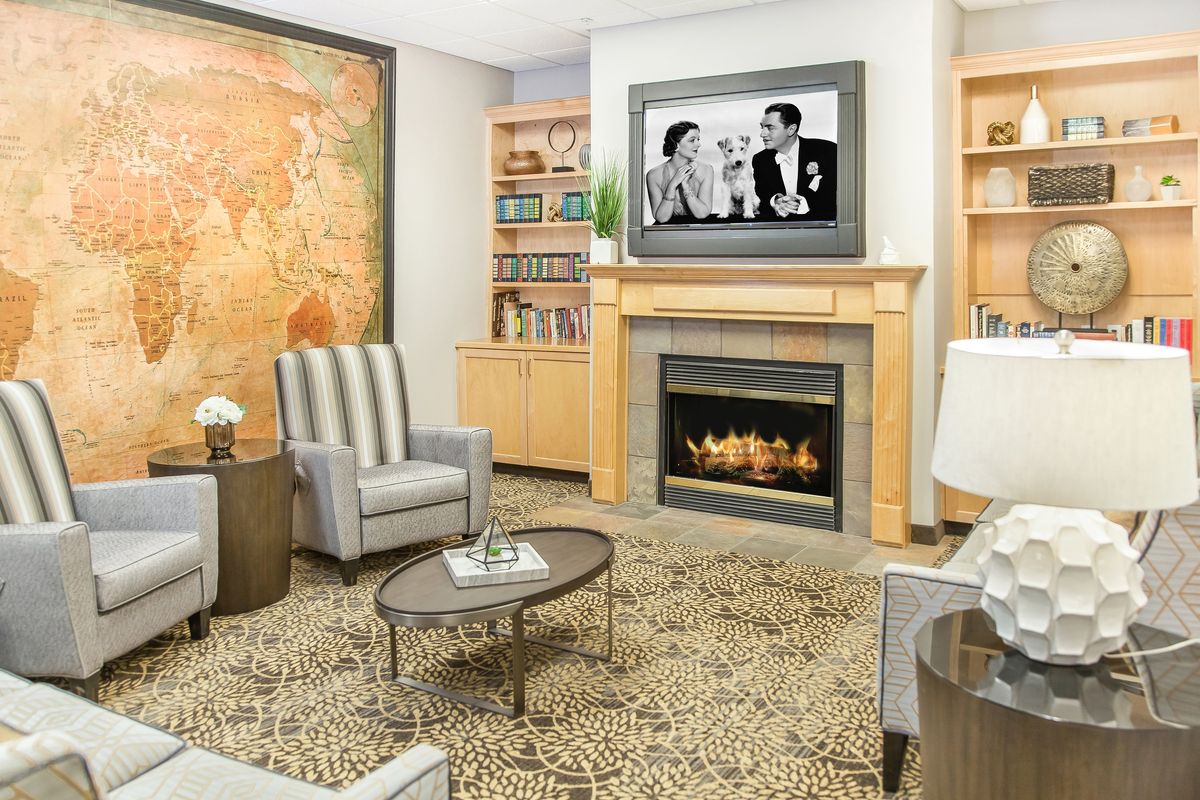 A modern living room featuring a fireplace, comfortable seating, and a television mounted above the mantel.
