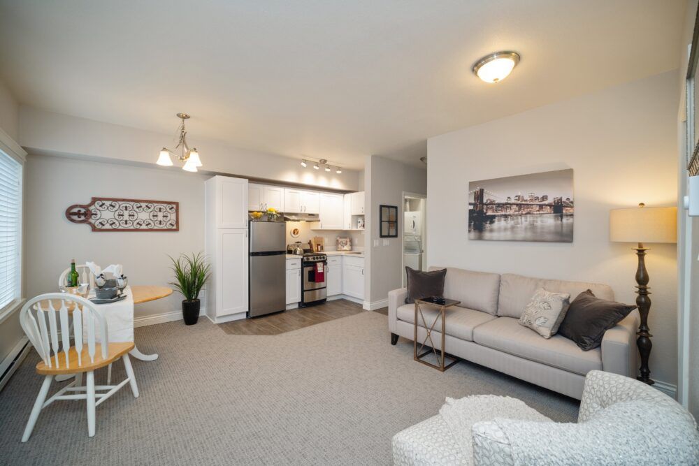 A modern open-concept living room and kitchen area in an apartment, featuring contemporary furniture and decor.