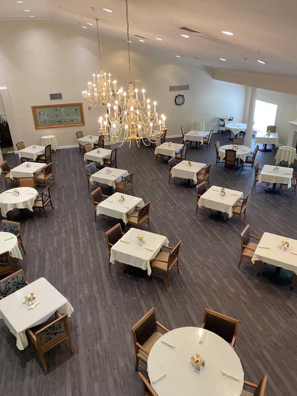 An elegant dining area featuring neatly arranged tables and chairs under a large chandelier.