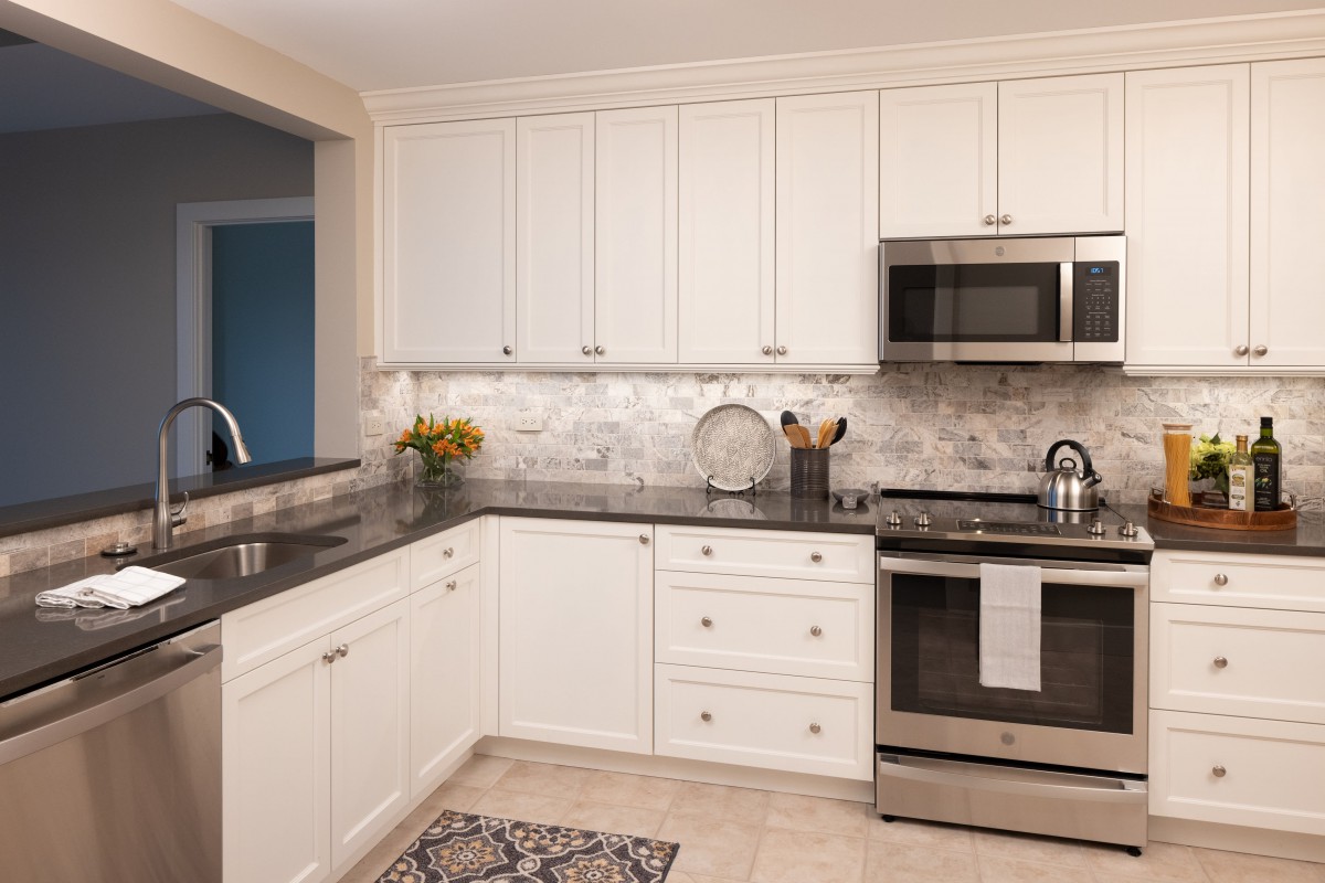 A modern kitchen with white cabinets and stainless steel appliances.