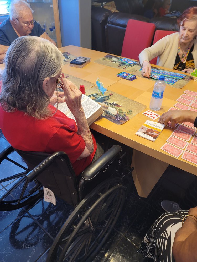 Elderly individuals engaged in a card game around a table.