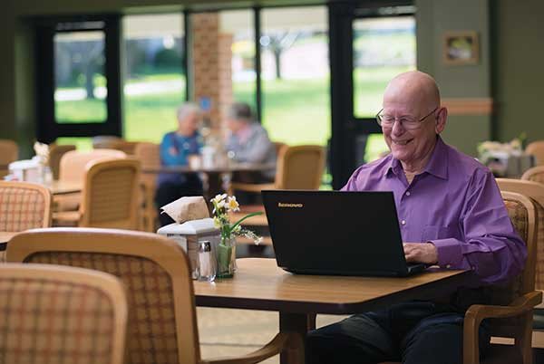 A senior individual using a laptop in a comfortable cafe environment.