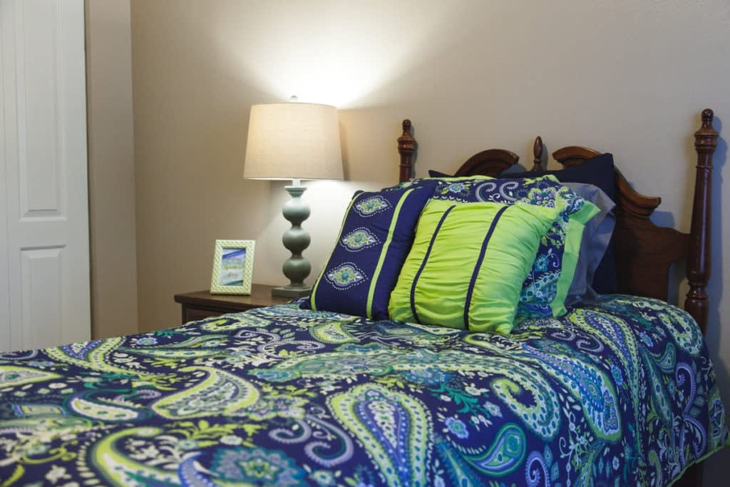 A cozy bedroom with a paisley-patterned bedding set and decorative pillows, accompanied by a stylish lamp.