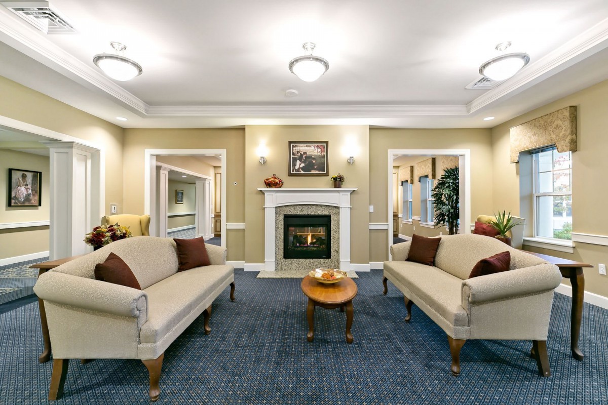 A cozy living room with elegant sofas, a central fireplace, and warm lighting.