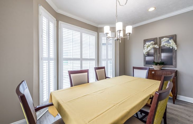 A well-lit dining room with a table, chairs, and a chandelier.