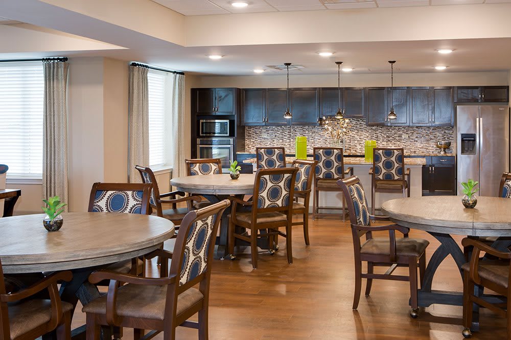 A modern dining area with tables, chairs, and a kitchen in the background.