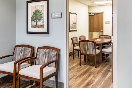 A well-designed waiting area leading to a meeting room, featuring comfortable wooden chairs and a calming decor.