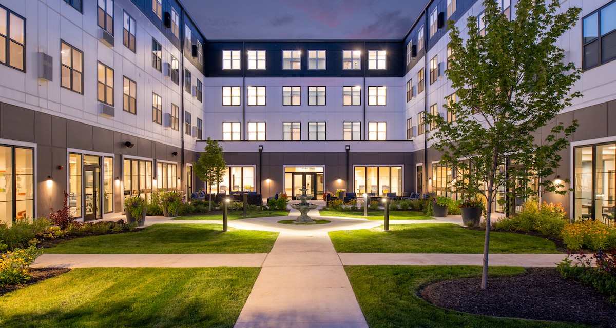 A beautifully illuminated building with a landscaped courtyard at night.