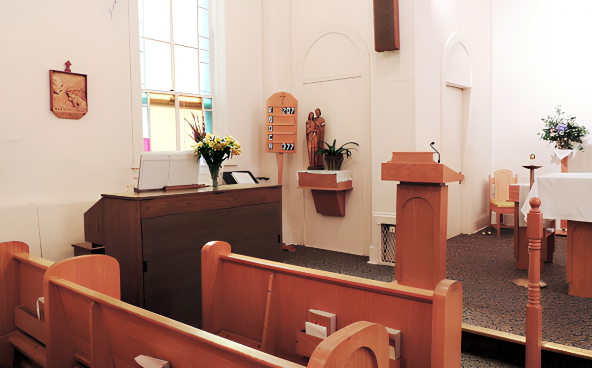Interior of a church with pews, a podium, and an altar.