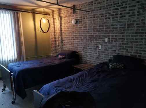 A cozy bedroom with two beds and an exposed brick wall.