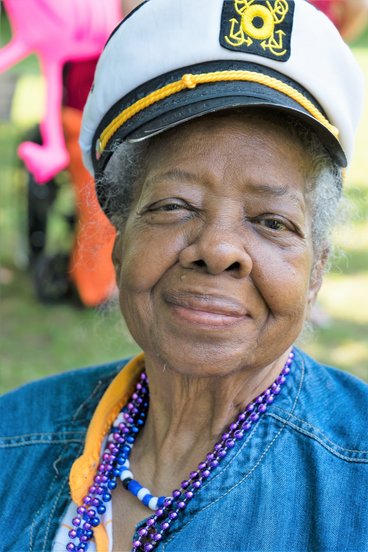 An elderly woman wearing a hat and smiling outdoors.