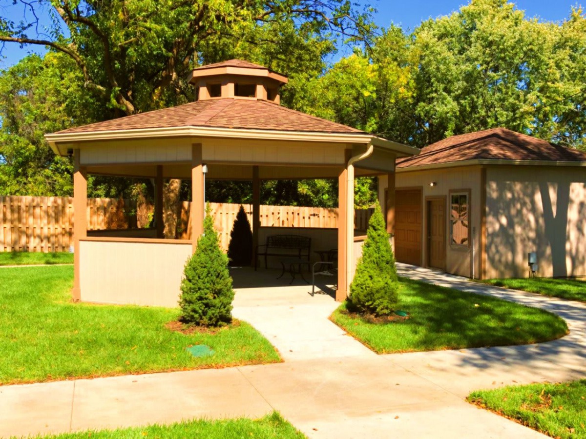 A charming gazebo surrounded by lush greenery and a well-maintained garden path.