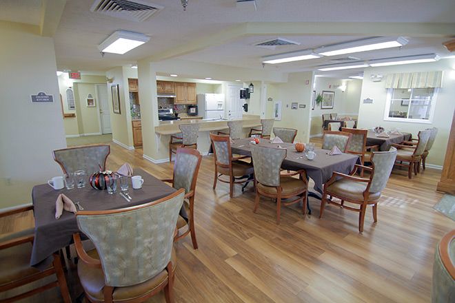 A cozy dining area with wooden floors and neatly arranged tables and chairs.