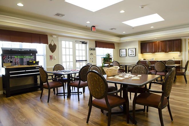 A well-lit dining area with wooden floors, multiple tables, and cushioned chairs.