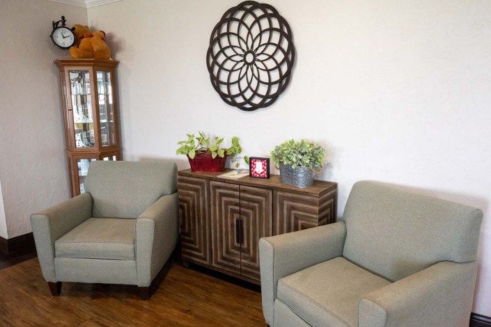 A cozy living room with two armchairs, a decorative cabinet, and wall art.