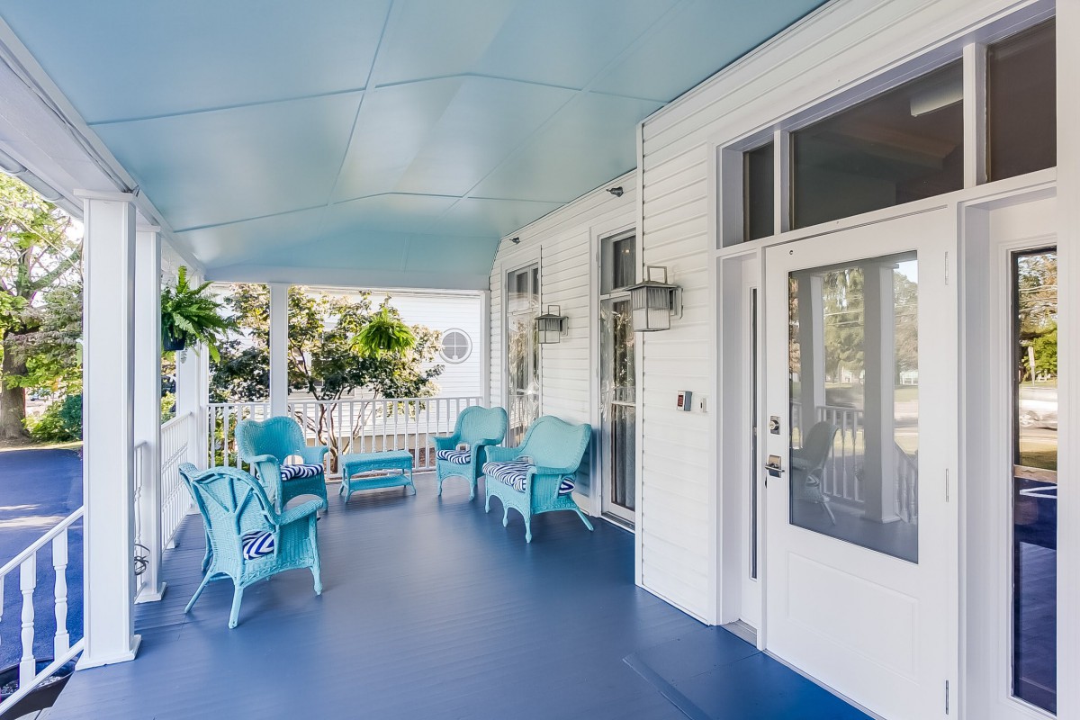 A charming porch with blue and white decor, featuring wicker furniture and plants.
