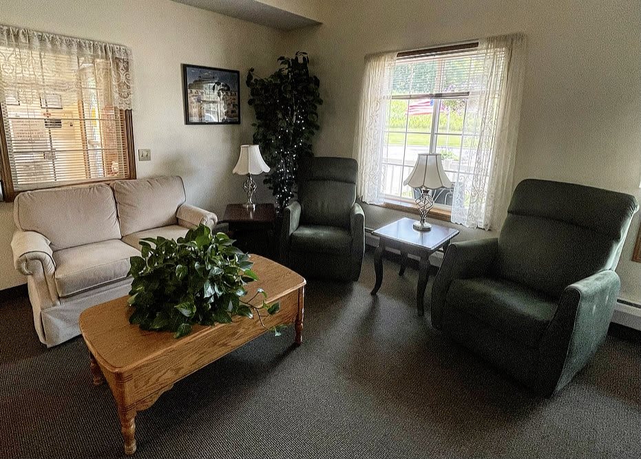 A cozy living room with a sofa, two armchairs, and a coffee table adorned with an indoor plant.