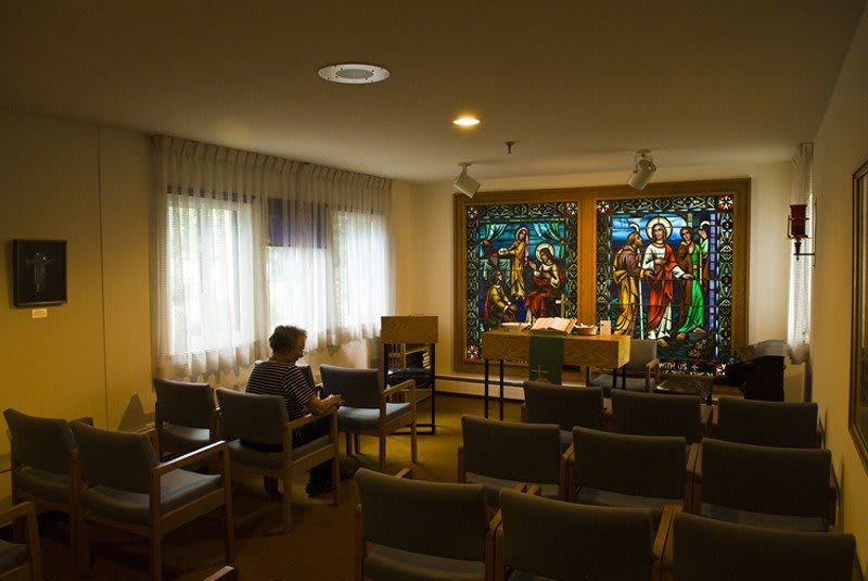 An empty chapel with stained glass windows and scattered seating.