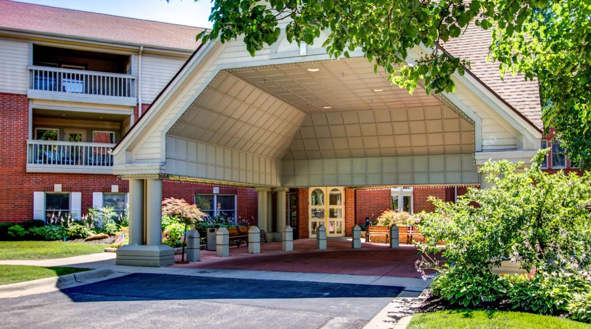 A building entrance with a covered walkway and surrounding greenery.