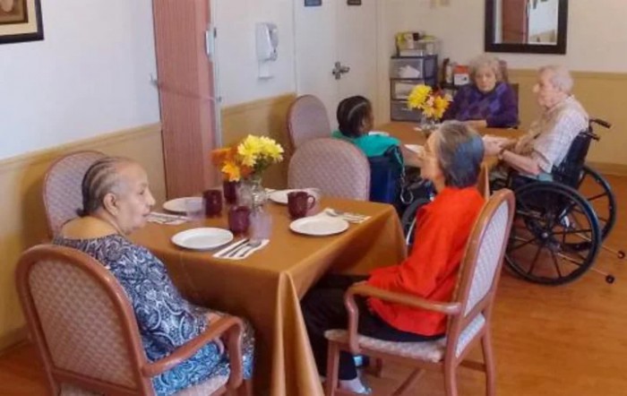 A group of senior individuals gathered around a table in a dining area, enjoying a meal together.