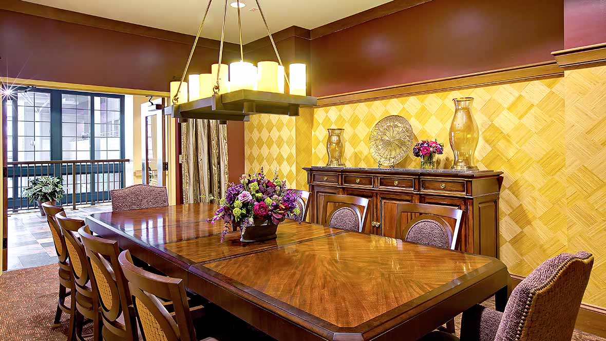 A warmly decorated dining room with a wooden table, chairs, and chandelier.