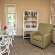 A cozy living room with an armchair, bookshelf, and glass table.