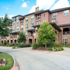 A scenic view of a multi-story residential apartment building with well-maintained landscaping.