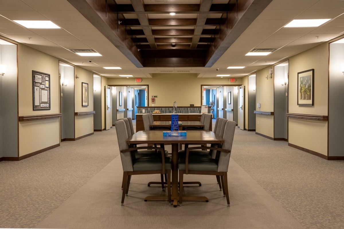A modern dining area with a central table and chairs, featuring elegant lighting and wooden accents.