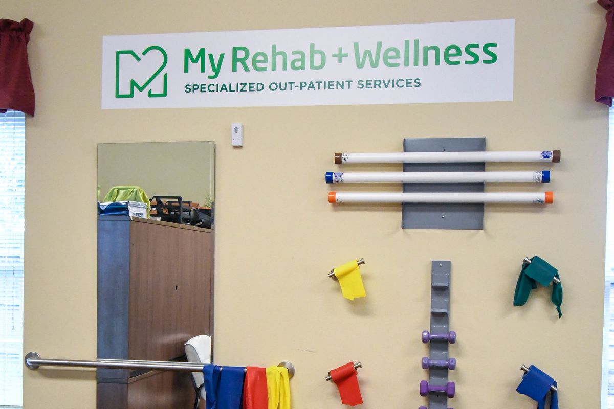 Interior view of a rehabilitation and wellness center showcasing therapeutic equipment and office signage.