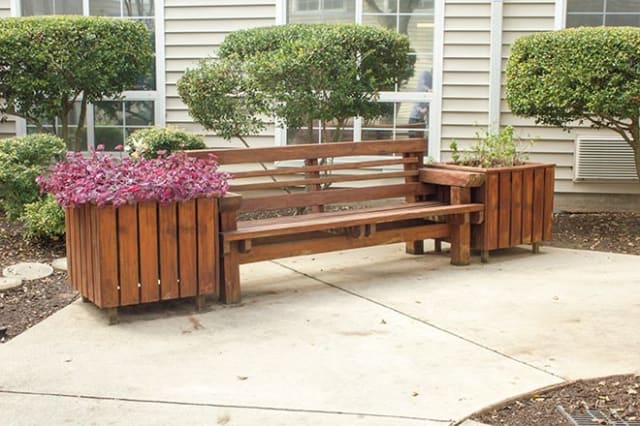 A wooden bench with integrated planters placed on a patio.