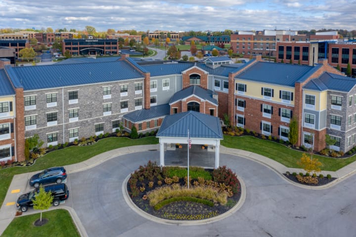 Aerial view of a modern hotel with landscaped gardens and parking area.