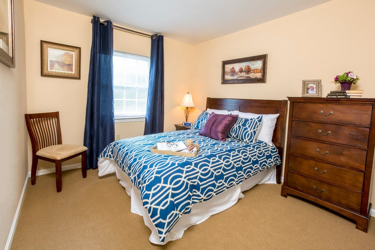 A cozy bedroom with a neatly made bed, decorative pillows, and a lamp on the nightstand.